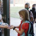 wearing masks prevent the spread of COVID-19 elementary school students use hand sanitizer before entering school for classes Godley, Texas.