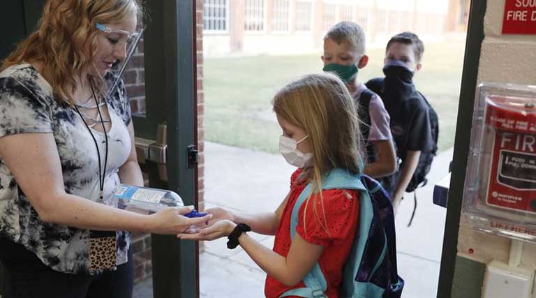 wearing masks prevent the spread of COVID-19 elementary school students use hand sanitizer before entering school for classes Godley, Texas.