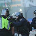 Police Department officers in anti-riot gear confront protestors in the streets